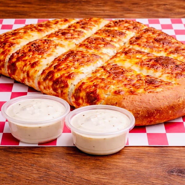 Cheesy breadsticks with two dipping sauces on red and white checkered paper.