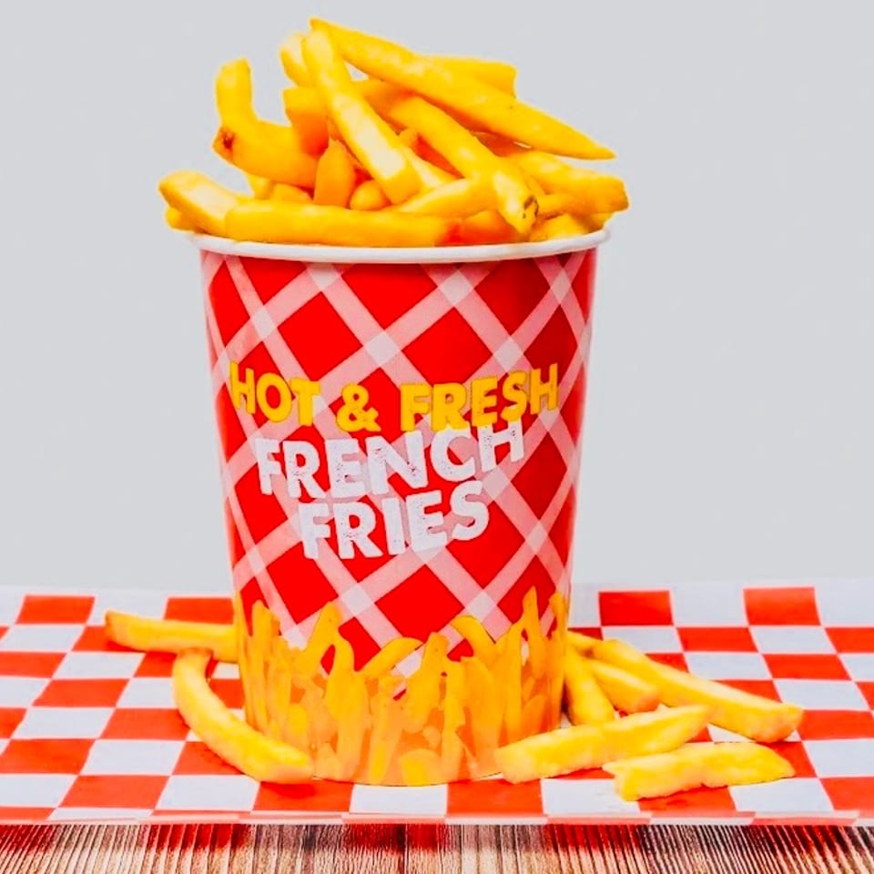 A red and white checkered cup overflowing with golden french fries on a matching paper liner.