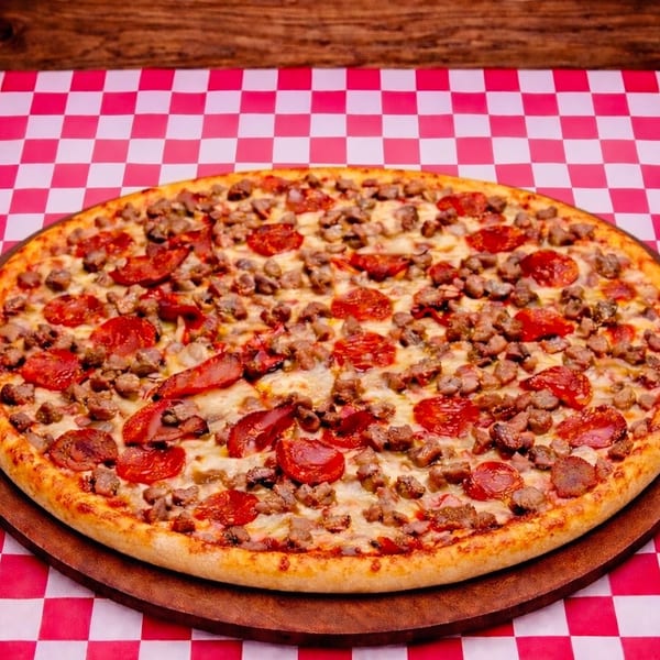 A large pepperoni and sausage pizza on a wooden board, resting on a red and white checkered tablecloth.