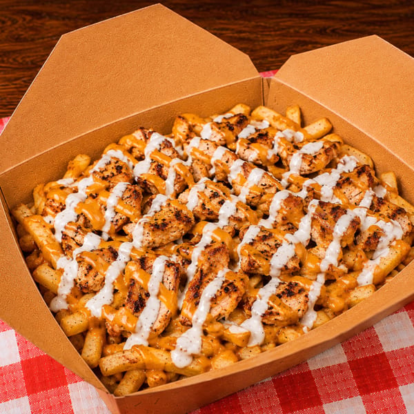 Loaded fries with grilled chicken, cheese sauce, and white garlic sauce in a takeout box.